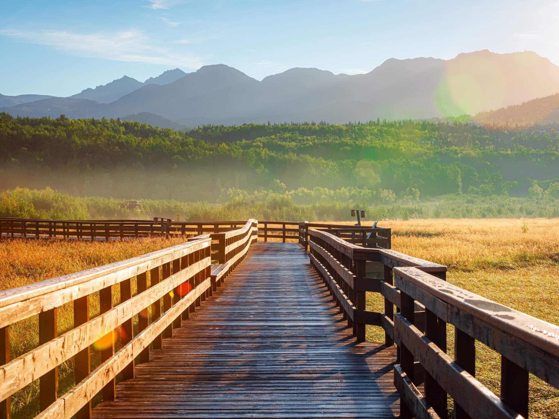A wooden boardwalk leading toward the mountains at Potter Marsh in Anchorage