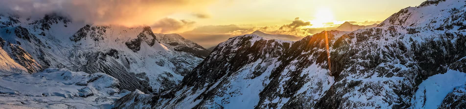 Snow-covered Alaska mountains beneath a glowing sky